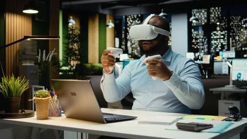 Black male worker using VR glasses and gadgets to draft a project plan Stock Photos