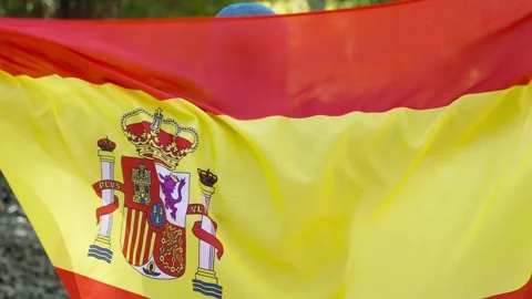 Black man from behind wrapped in big spanish flag unfold the flag Stock Footage 287487304