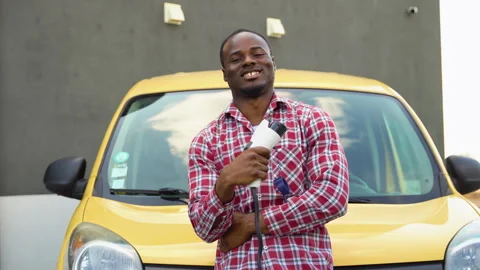 Black man with charging cable at electro charging station near cargo electric Video stock 249086770