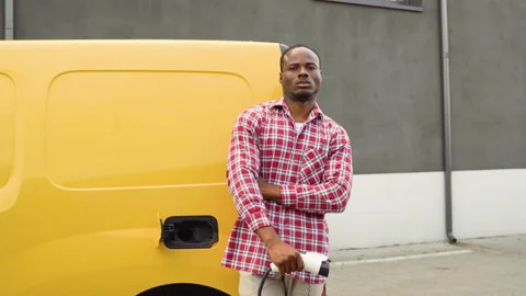 Black man with charging cable at electro charging station near cargo electric Video stock 249089625