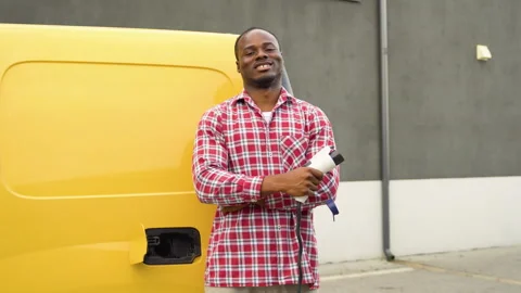 Black man with charging cable at electro charging station near cargo electric Video stock 249090031