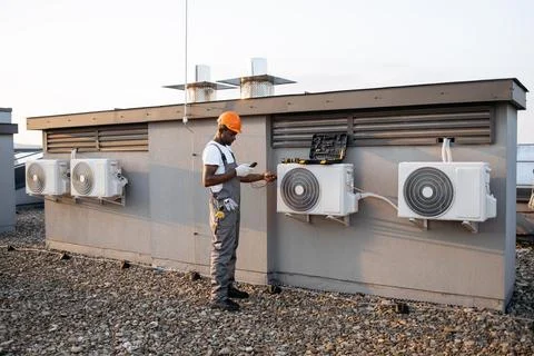 Black man checking air conditioner with digital multimeter Stock Photos
