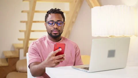 Black man checking email and messengers in smartphone when working at home Stock Footage 262691446