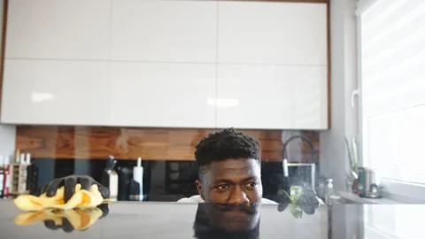 Black man cleaning kitchen. Surface reflects his face Stock Photos