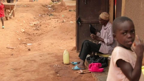Black man cleans shoes in African slum street, poor district Uganda Kampala life Stock Footage 211124341