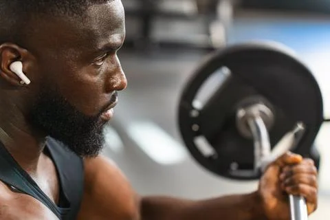 Black man concentrating while training his arms with the barbell Stock Photos