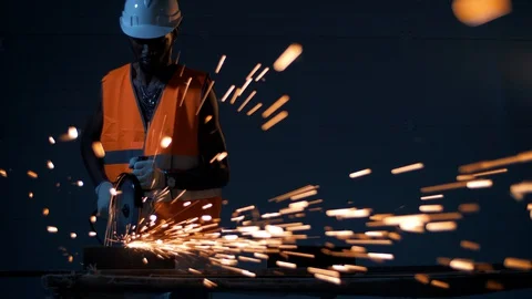 A black man in a construction uniform works with a circular saw and sparks fly Stock Footage 128748426