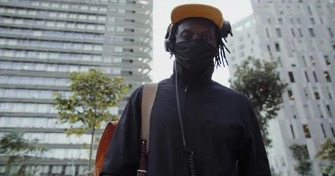 Black man dancing and listens to music in headphones and a smartphone on a city 動画素材 202324117