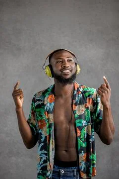 Black man dancing while listening to music in headphones against gray background Stock Photos