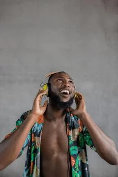 Black man dancing while listening to music in headphones against gray background Stock Photos