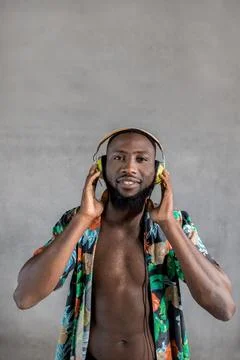Black man dancing while listening to music in headphones against gray background Stock Photos