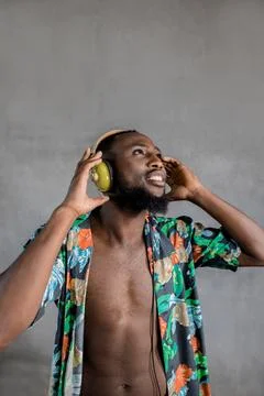 Black man dancing while listening to music in headphones against gray background Stock Photos