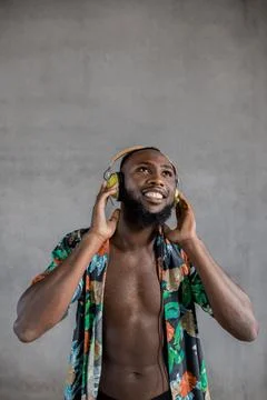 Black man dancing while listening to music in headphones against gray background Stock Photos
