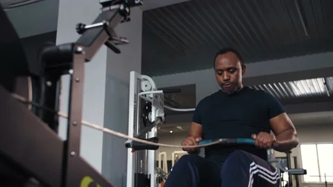 Black man do exercises With Rowing Machine in gym.Fitness Young strength athlete Stock Footage 225717612