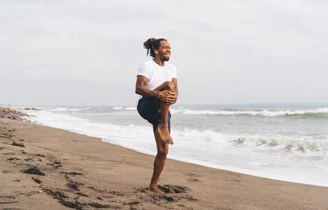 Black man doing exercises on beach Stock Photos