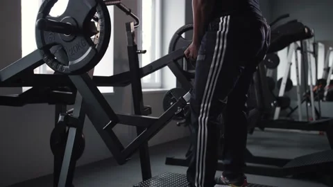Black man doing leg workout in gym.Athlete training in gym machine doing squats Stock Footage 225715797