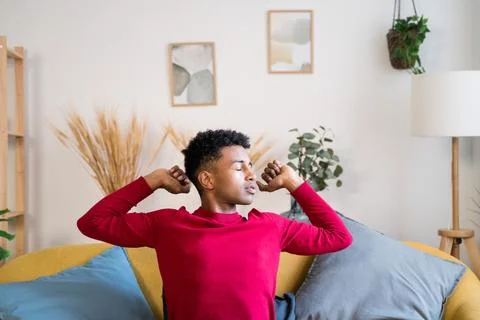 Black man doing stretching exercises on sofa at home Stock Photos