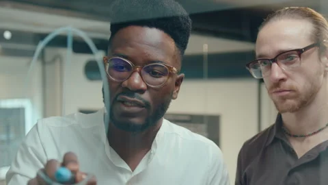 Black Man Drawing Chart on Glass Office Wall and Talking with Colleague Video stock 258725436