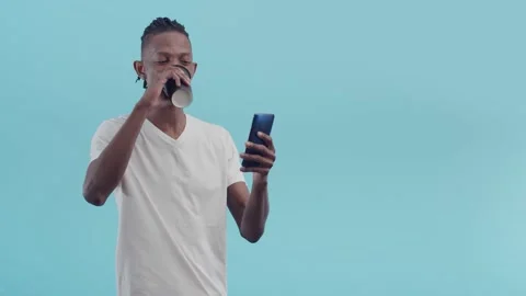 Black man with dreadlocks speaks via video link on the phone and smiles drinking Stock Footage 156792772