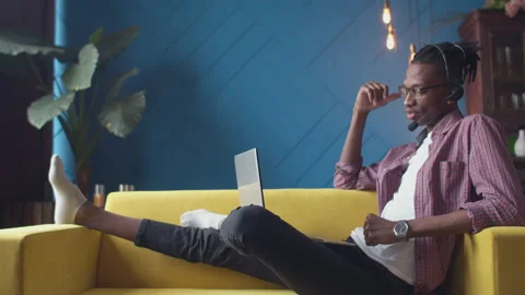 Black man with dreadlocks wearing glasses and a headset is talking on a video Stock Footage 155884227