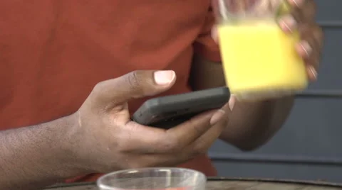 A black man drinks juice and uses cell phone - close-up Stock Footage 44227241
