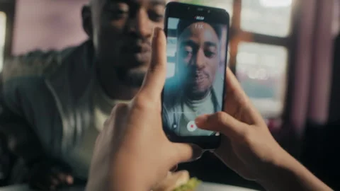 Black man eating a burger while being recorded with a phone Stock Footage 275127014