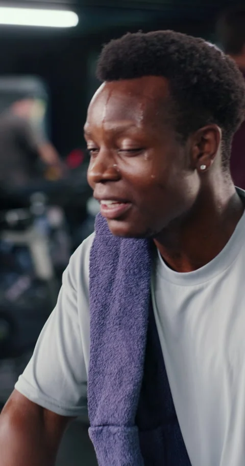 Black man, face and tired at gym with sweat, towel and happy with exercise, Stock Footage 326986599