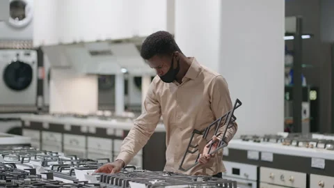 Black man with face mask is choosing stove for new kitchen in apartment Stock Footage 153012018