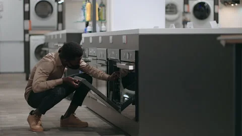 Black man with face mask is viewing electric oven in home appliances store, afro Stock Footage 153198360