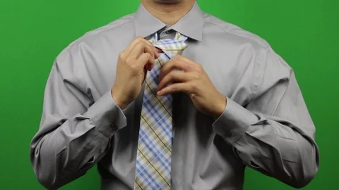 Black man In Grey Button Down Shirt Tying Necktie In Front Of Green Screen Stock Footage 87269840