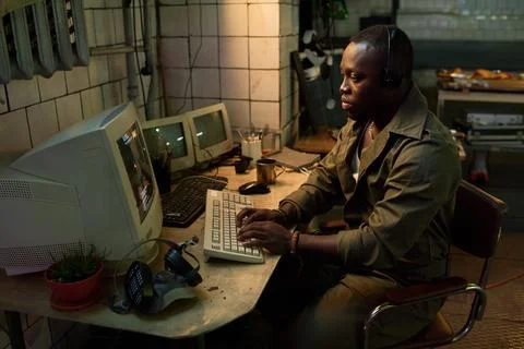 Black Man Hacking Code On Computer In Abandoned Building Foto stock