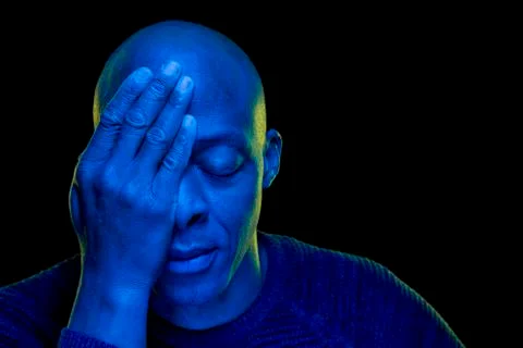 Black man with hand in eye and the other closed. Studio photo with blue light Stock Photos