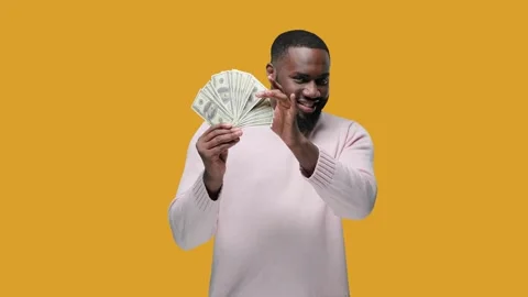 Black man handsome blinking winking rich man shows a pack of dollars on yellow Stock Footage 142580633