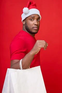 Black man in hat looks at the camera and holds white paper bags in his hands Stock Photos