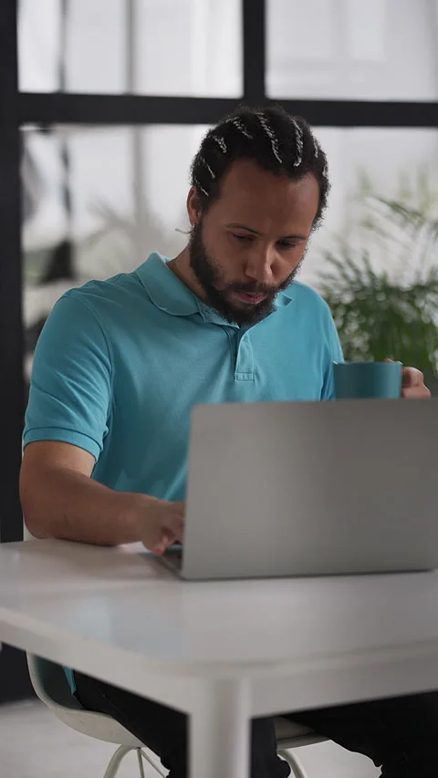 Black man in his 20s typing on a laptop, working on an online project from home Stock Footage 333782079