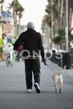 Black Man Holding Basketball And Walking Dog