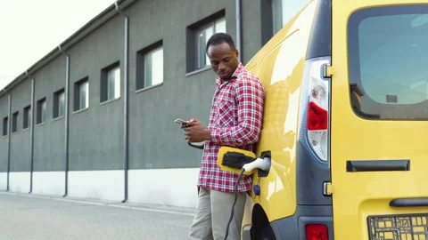 Black man holding smartphone while charging truck car at electric vehicle Video stock 249088634