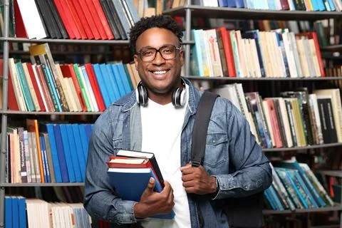 Black man holding a stack of books, looking at the camera and smiling broadly Stock Photos