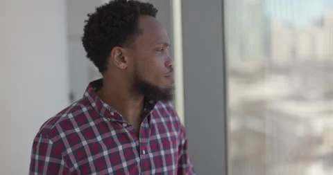 Black man at home standing by a window sad and depressed Stock-Footage 169428387