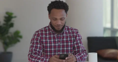 Black man at home using smartphone texting Video stock 169423849