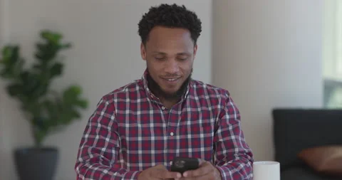 Black man at home using smartphone texting Stock Footage 169426797