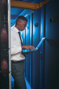 Black man, laptop and coding with typing in server room with review, system test Stock-Fotos