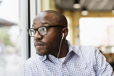 Black man listening to earphones in coffee shop Stock Photos