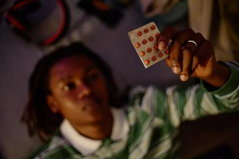 Black Man Looking at Blister Pack of Medication at Home Stock Photos