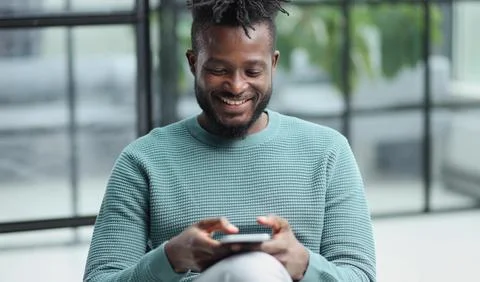 Black man looking at smartphone browsing internet, office technology and digital Stock Photos