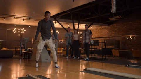 A black man makes a throw in a bowling club and enjoys emotionally knocking out Stock Footage 168230472