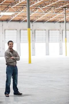 Black man owner of a new warehouse standing inside in front of loading dock Stock Photos