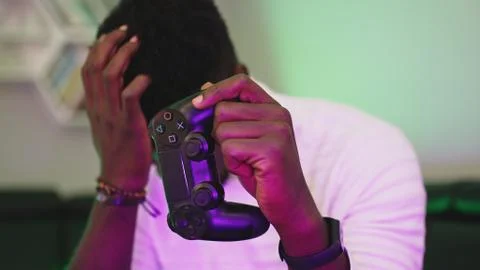 Black man playing game using console controlling joystick. Entertainment during Stock Photos
