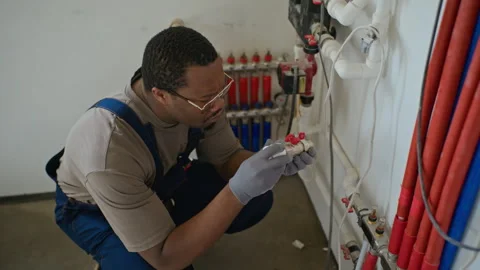Black Man Plumber Inspecting Water Valve during Renovation Stock Footage 340614560