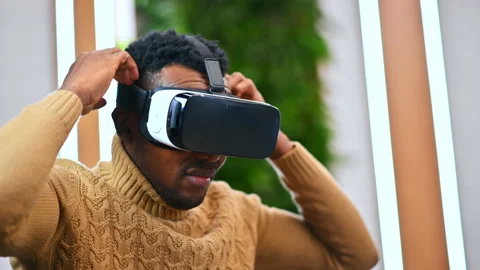 A black man putting on VR glasses in an office and starts exploring virtual Stock Footage 235224368